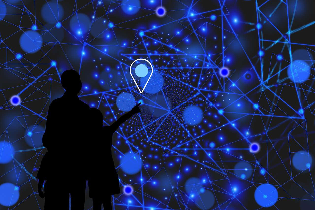 Zwei Menschen, wobei der eine auf einen Standortmarker auf einem blauschwarzem Netzwerk zeigt.